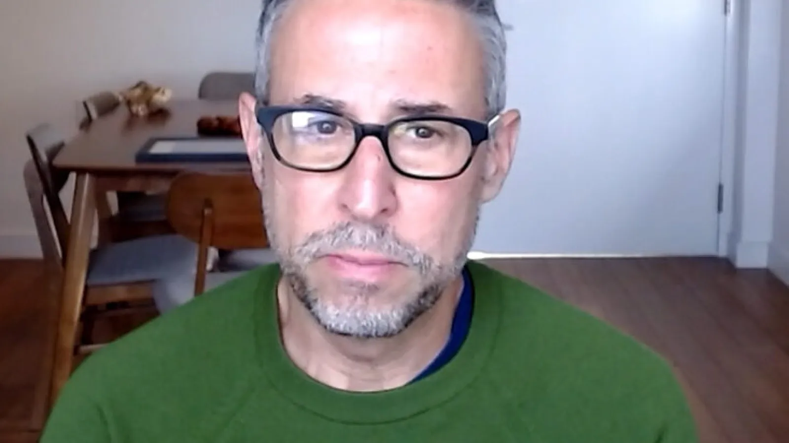 Serious man with green shirt and black glasses