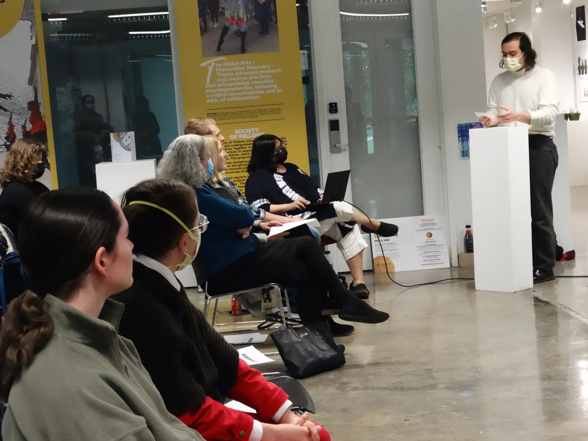 Crowd watches a person present at a white podium