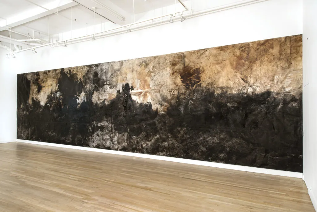 Large abstract painting covering the wall of a gallery in shades of brown and black