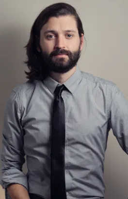 man in button up and tie smiles in headshot