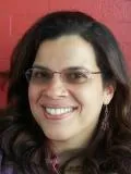 Smiling woman with long dark hair and glasses in from tof red wall